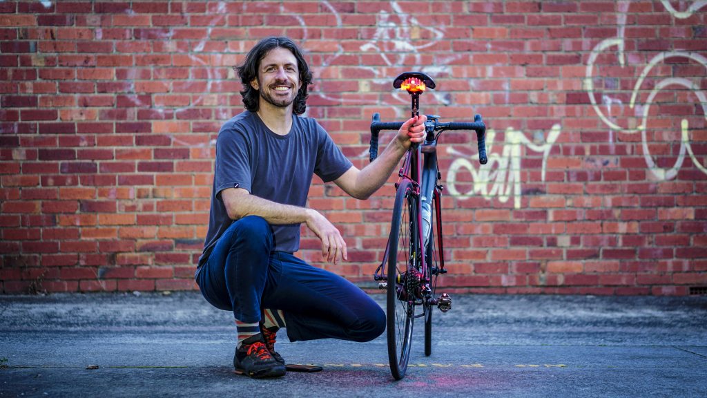 Tim Ottaway posing with his Project Flock bike light attached to a bike