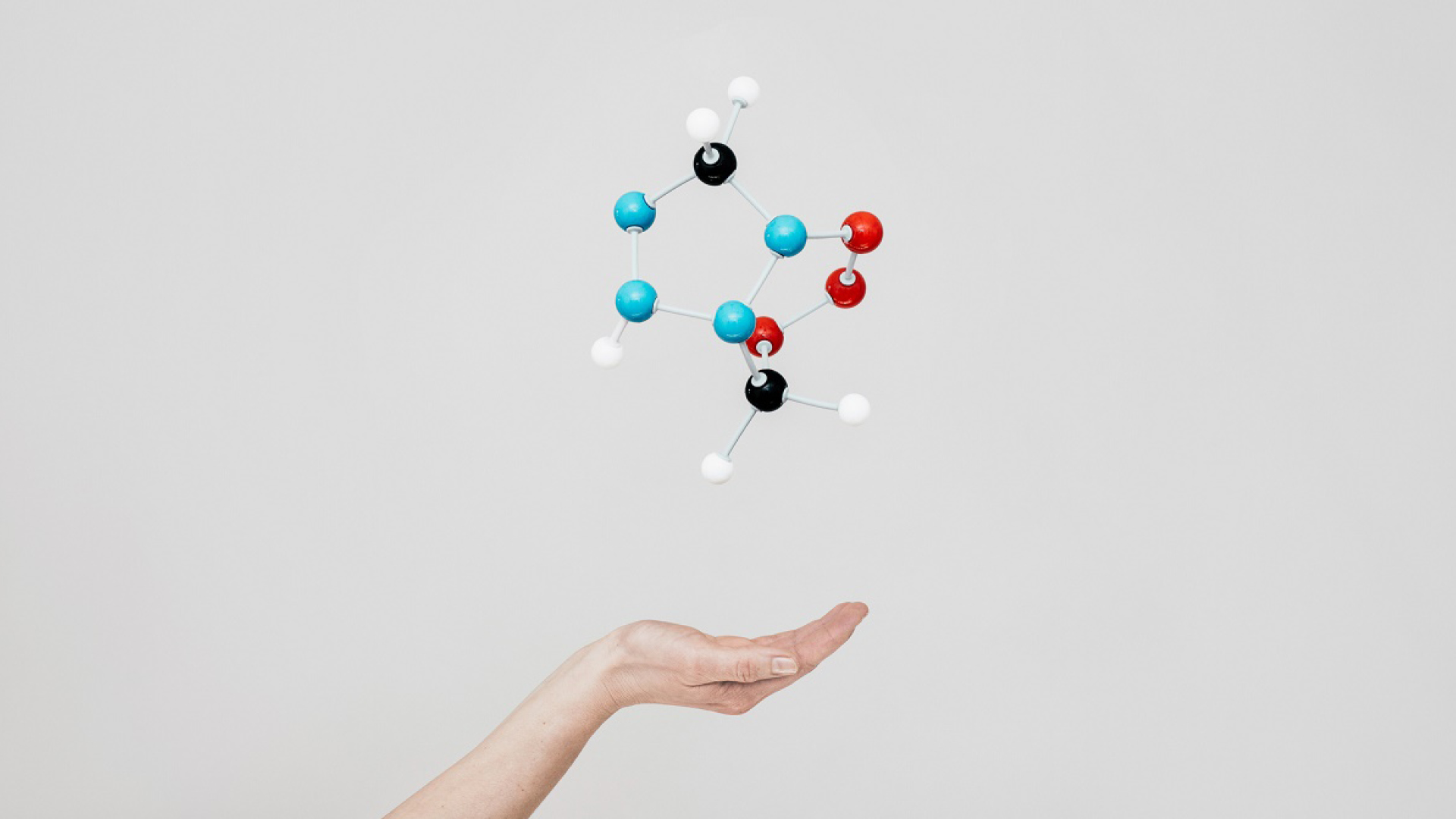 A cupped hand with model atoms suspended above