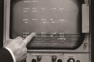Black and white screen of air traffic control radar with finger pressing touchscreen