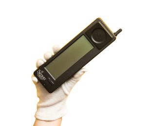 A gloved hand holding the first smartphone with a touchscreen: IBM Simon