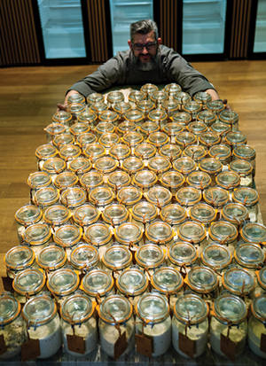 Sourdough librarian Karl De Smedt with his arms around some jars of his sourdough starter collection.