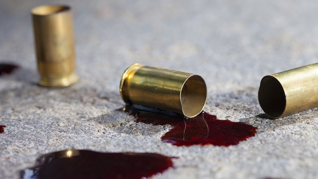 Empty bullet casings on the ground with pools of blood